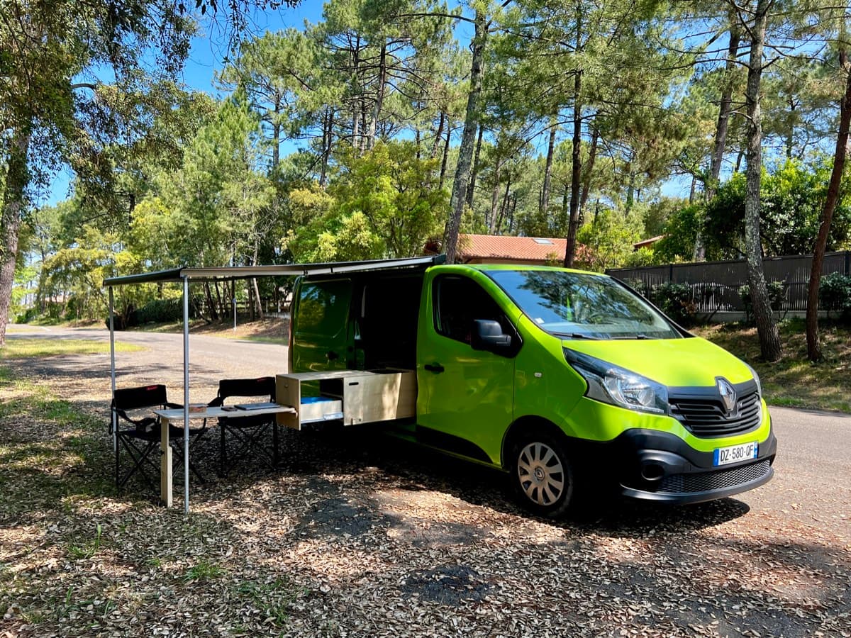 Renault Trafic aménagé Vanzon garé en forêt, portes ouvertes, proposé à la vente