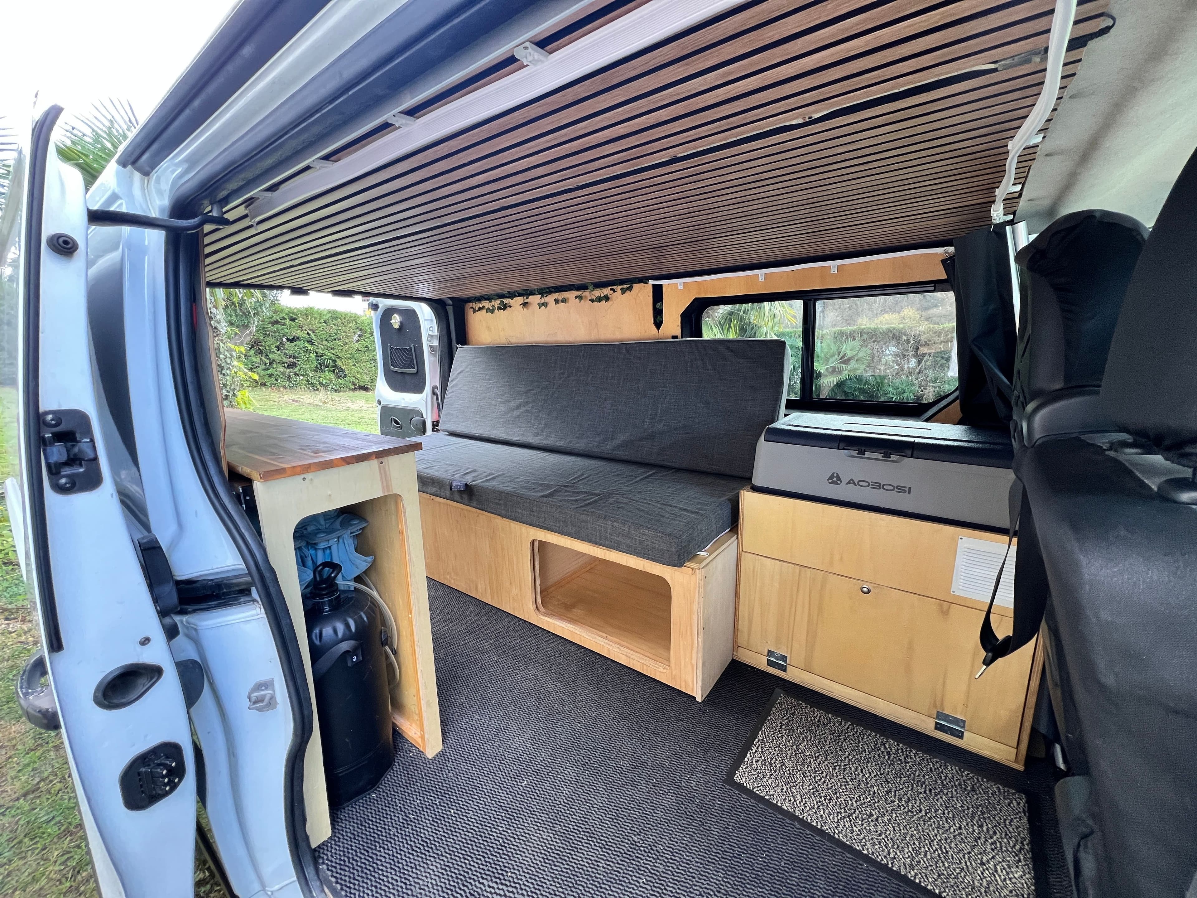 Interieur du van amenage Xalbat, banquette et cuisine en lumiere naturelle — Vanzon Explorer