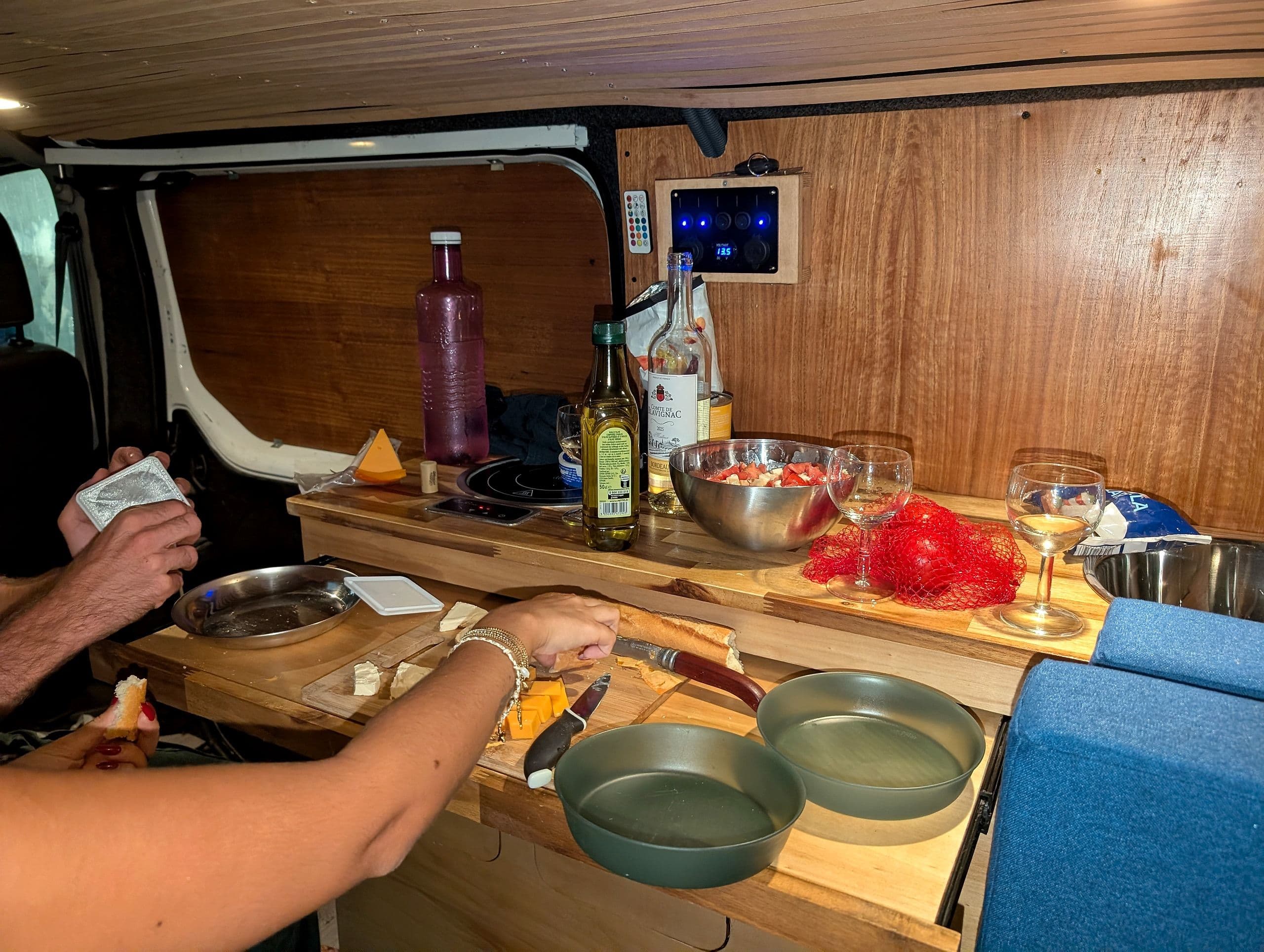 Apéro sans frigo préparé dans la cuisine latérale d'un van Vanzon Explorer : pain, fromage, tomates et huile d'olive